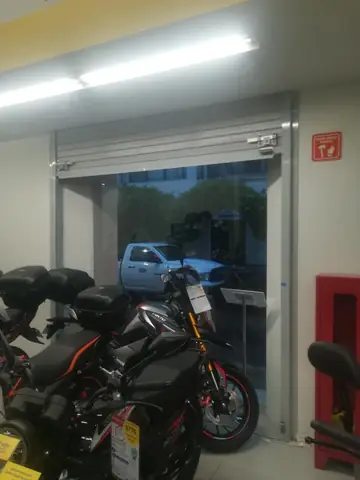 Acceso con cortina metálica y motocicletas en exhibición