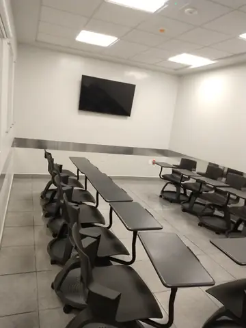 Sala de capacitación con mesas y pantalla