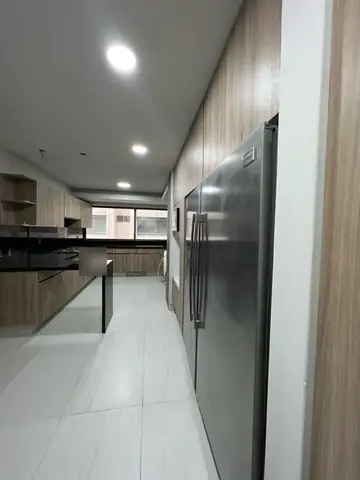 Cocina terminada: pasillo con refrigeradores de acero y gabinetes de madera
