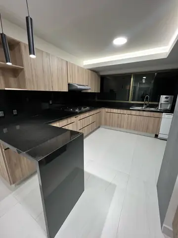 Cocina terminada: vista en L con barra de granito