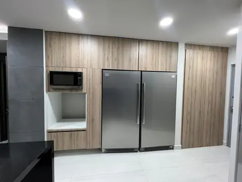 Cocina terminada: refrigerador doble de acero, microondas empotrado y gabinetes de madera