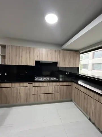 Cocina terminada: vista en L con parrilla, cubierta negra y ventana